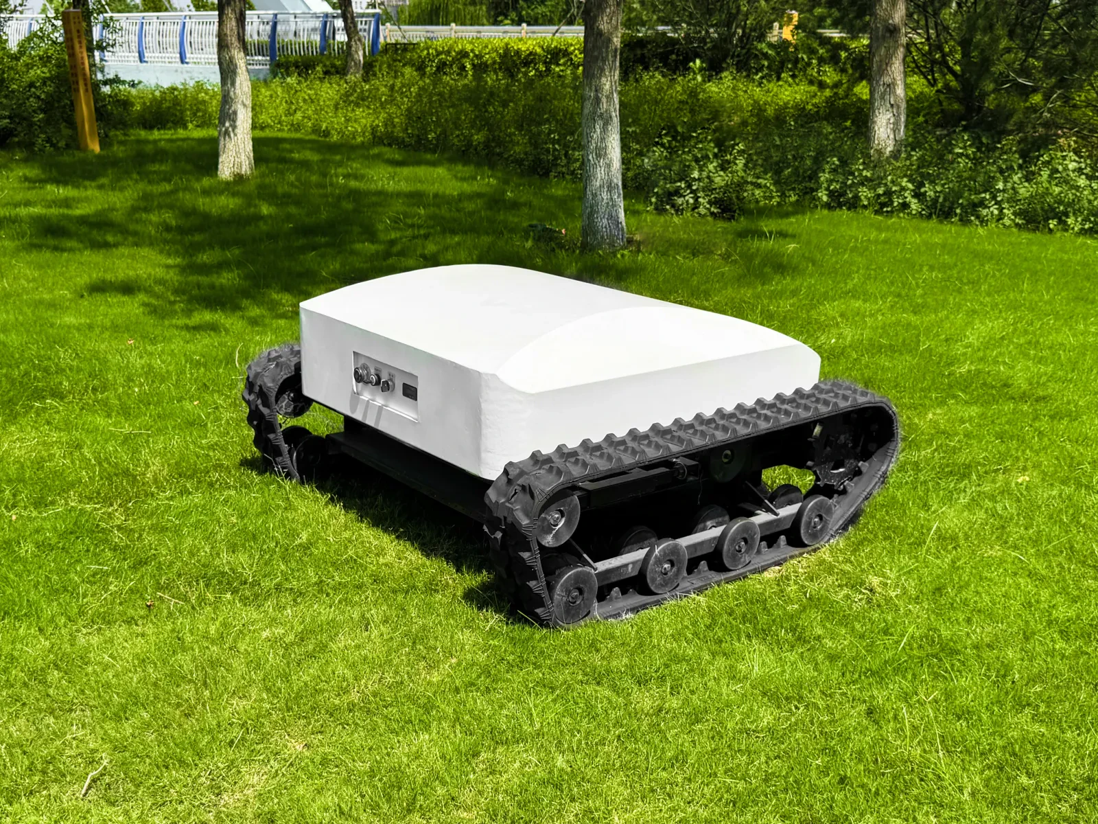 White tracked mower photographed on a landscaped grass site