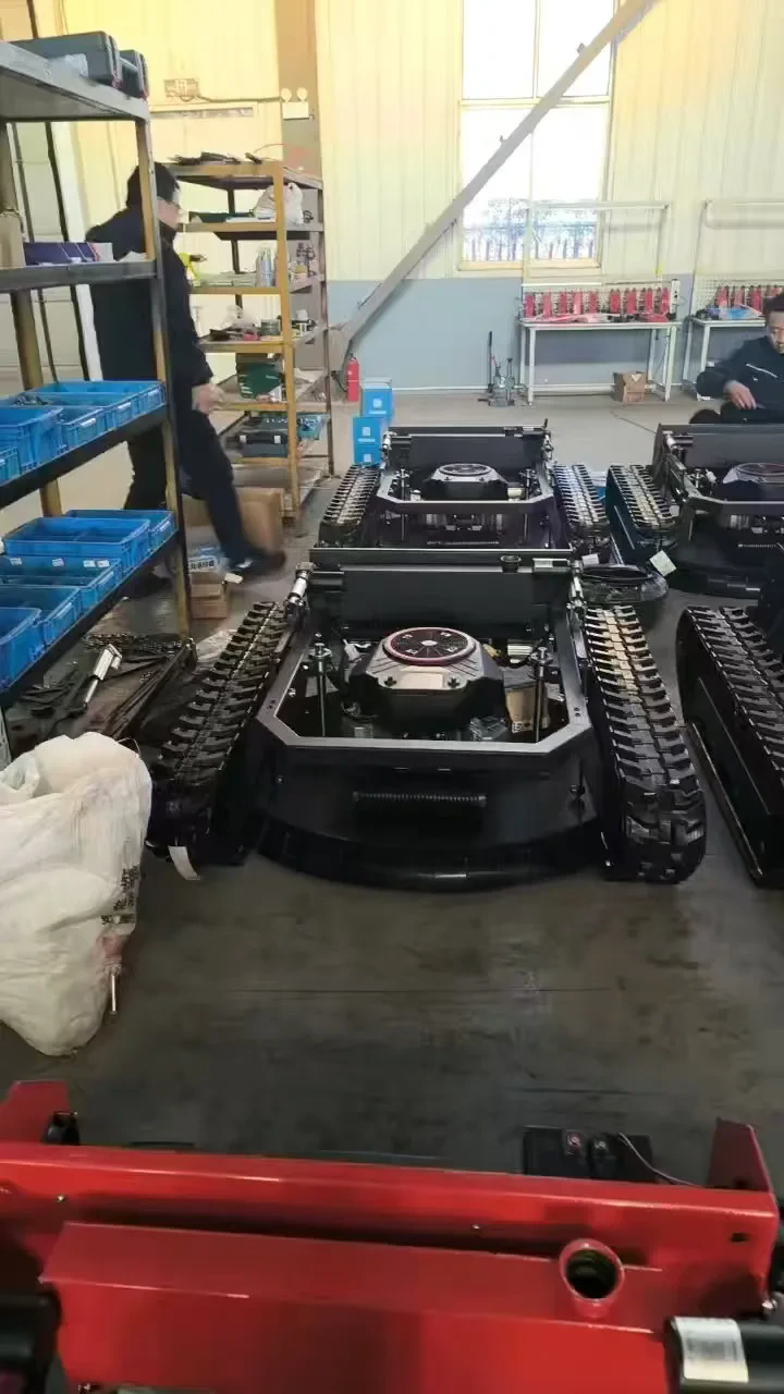 Tracked mower chassis arranged beside parts shelves during assembly work